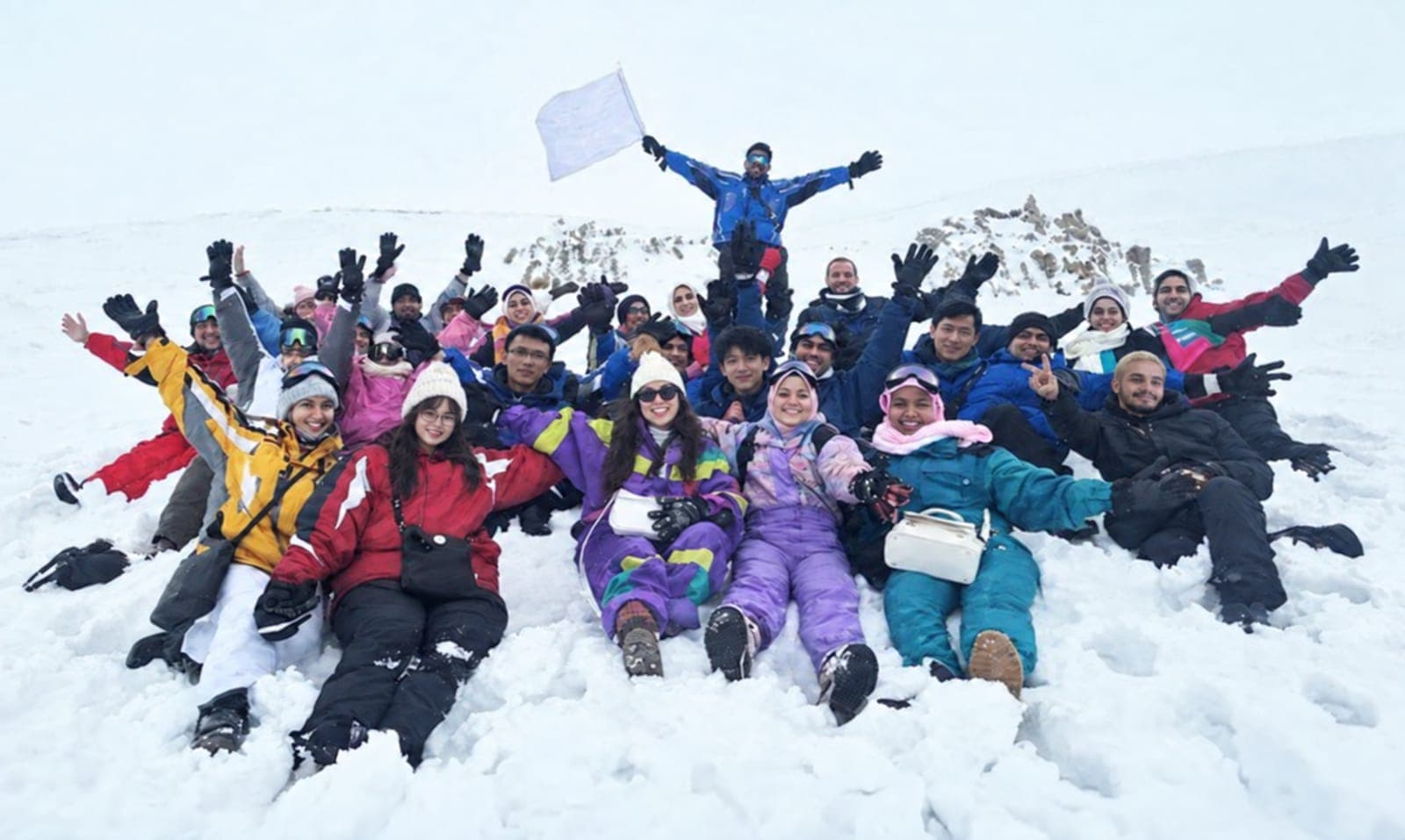 A large group cheering in the snow on a ski trip